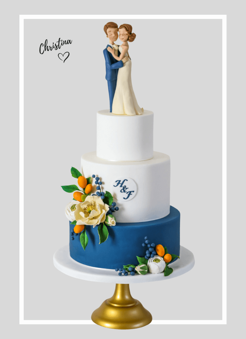Custom Mediterranean coloured Wedding cake, white navey blue with kumquats, blueberries and open rosed sugar flowers, topped with handmade personalised wedding cake figures lovingly